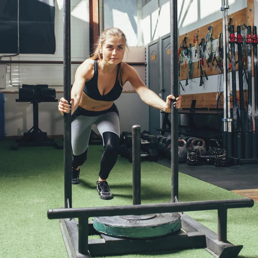 athletic female pushing a sled in a gym