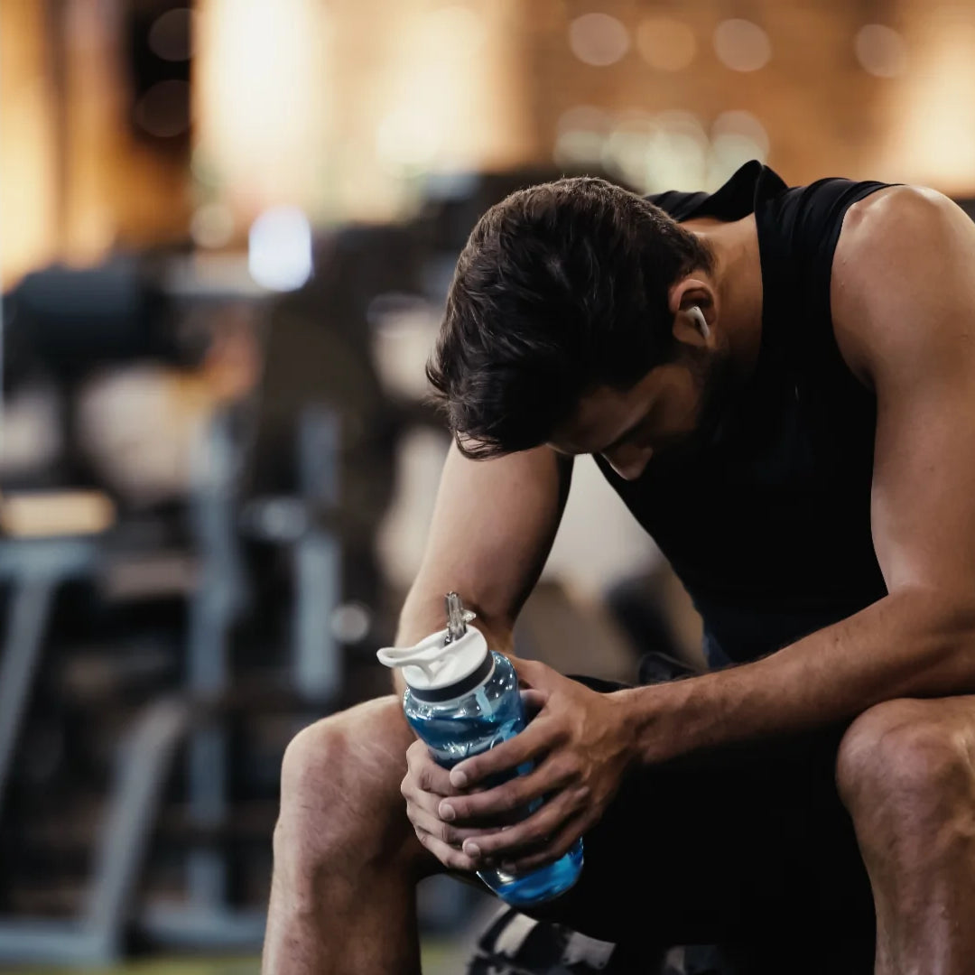 man holding a bottle of water in a gym after a hard workout