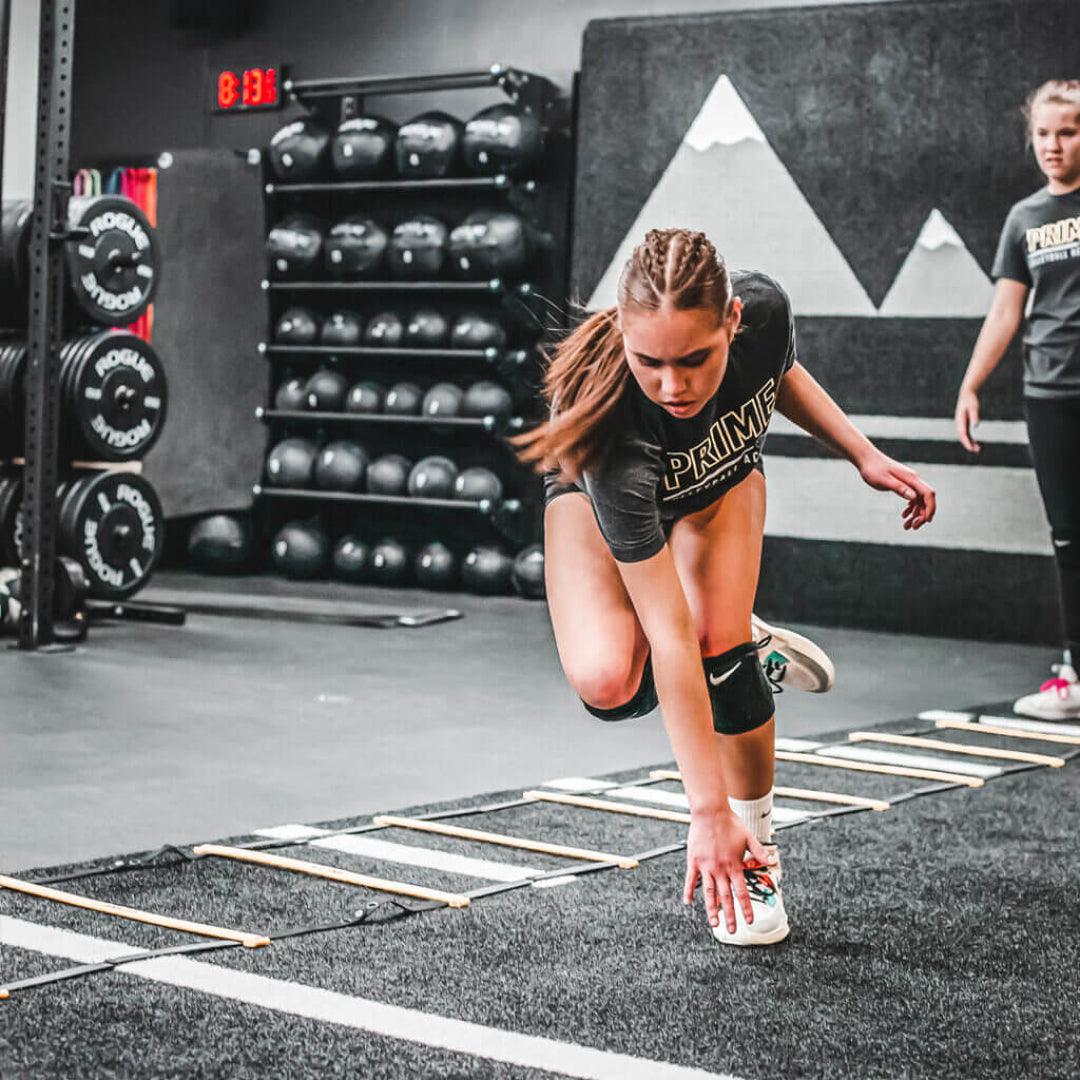 young female athlete speed training on an agility track in a gym