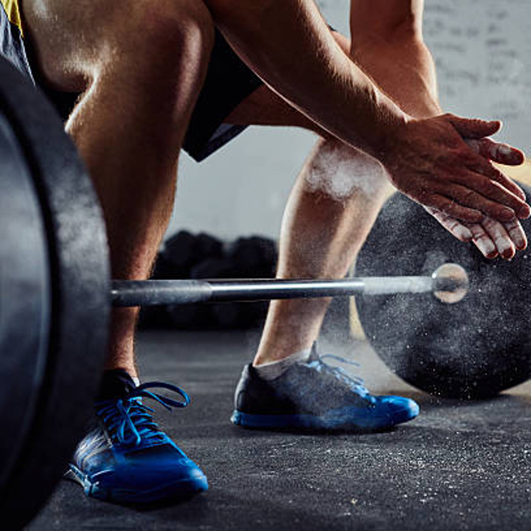 close up of a athletic male squatting down with a loaded barbell