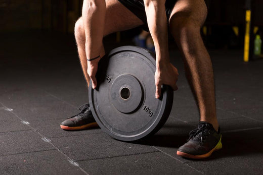 Person using weight plates on a rubber gym floor